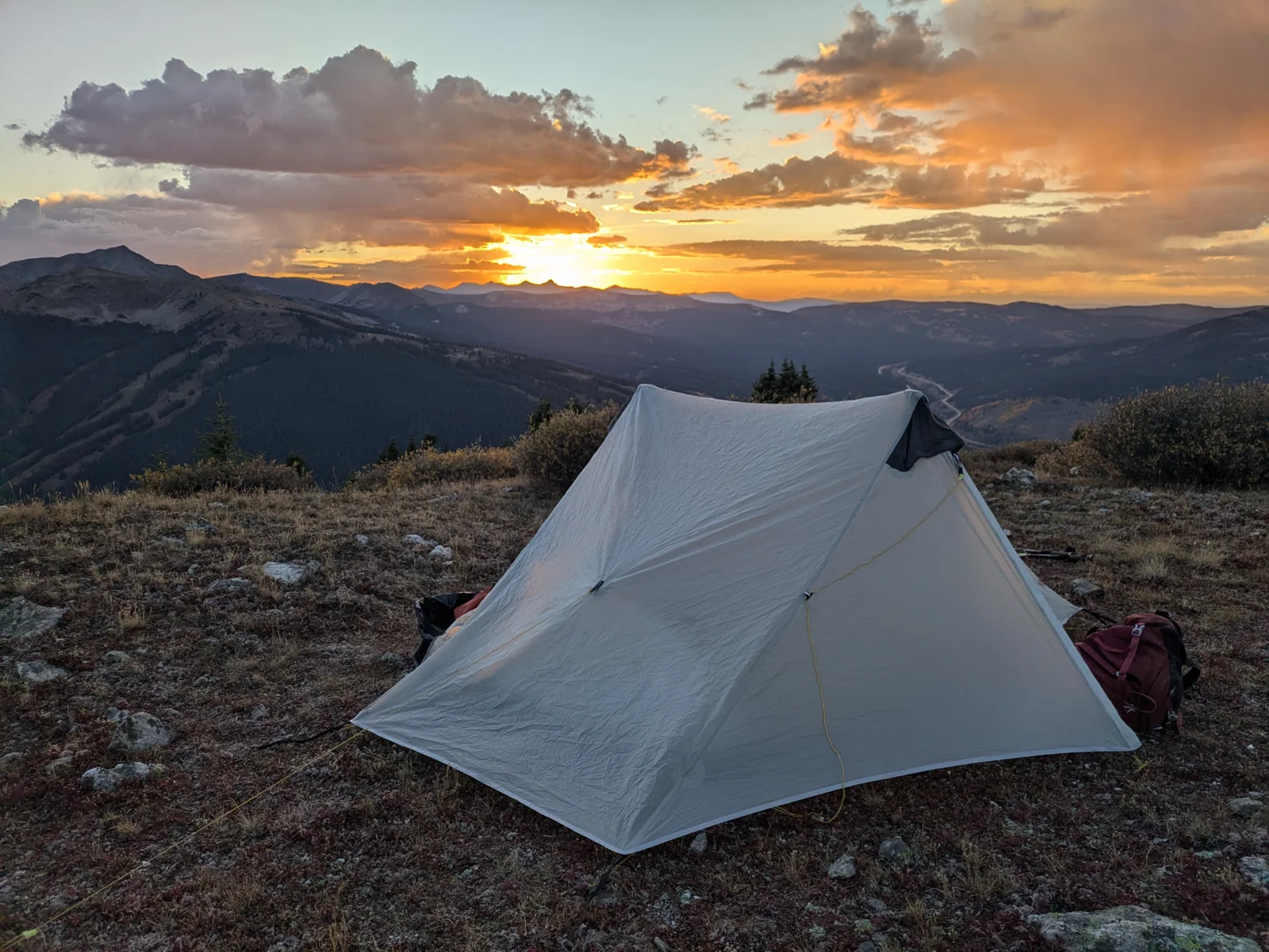 Abbey’s tent pitched on rocky terrain at sunset, with mountains beyond